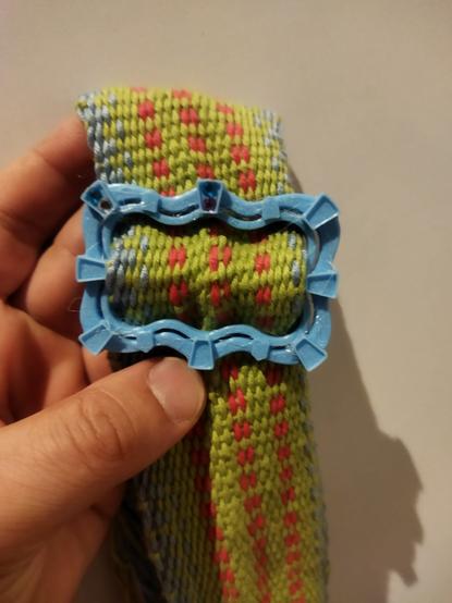 Drukowana na drukarce 3d ozdobna sprzączka  nanizana na tkany pasek. Sprzączka ma ozdobne wnęki. W dwie z nich włożone cekiny-kryształki