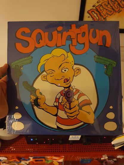 Cover of Squirtgun Lp. you see a comic dude with squirtguns aiming at the viewer