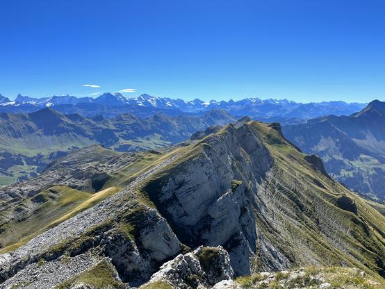 Foto einer felsigen Bergkette, im Fernen Hintergrund ein Bergpanorama