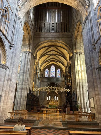 Inside of Hereford Cathedral, a view of the altar with the massive pillars on either side and the beautiful curved ceiling.