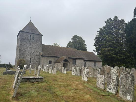And old church amidst old gravestones. The sky is dark and grey.