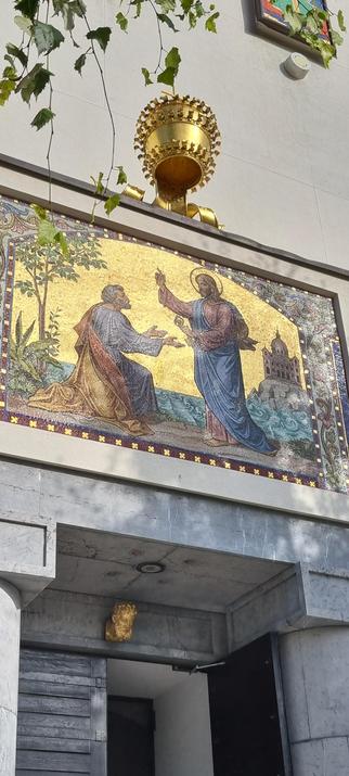 Foto von Kunst an der Außenwand der Kirche Svetega Petra (Petruskirche). Das Kinstwerk zeigt Jesus, der dem knienden Petrus einen Schlüssel reicht.