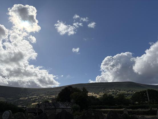 View of Black Mountains, a blue sky with towering white clouds on either side of the frame.