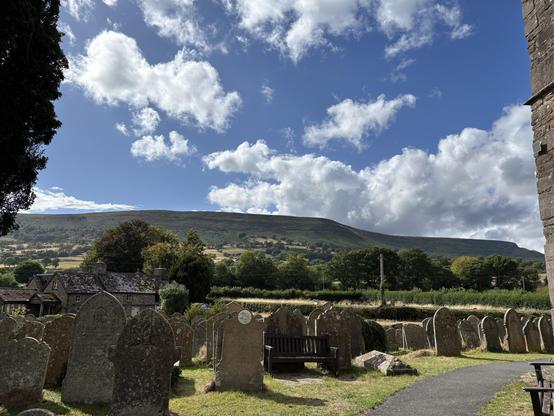 View from the church bench. In the foreground are gravestones with the Black Mountain hills in the background against a blue sky