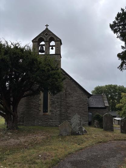 View of a church with an exposed clock tower containing one large and one small bell.
