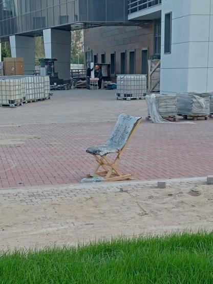 На строительной площадке стоит почти дизайнерское кресло, сделанное из палок и, кажется, листа рубероида