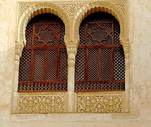 2 geschwungene Fenster in der Alhambra. Die Fenster an sihh sind Braun, darum gleicher Sandstein mit wunderschönen Ornamentationen.