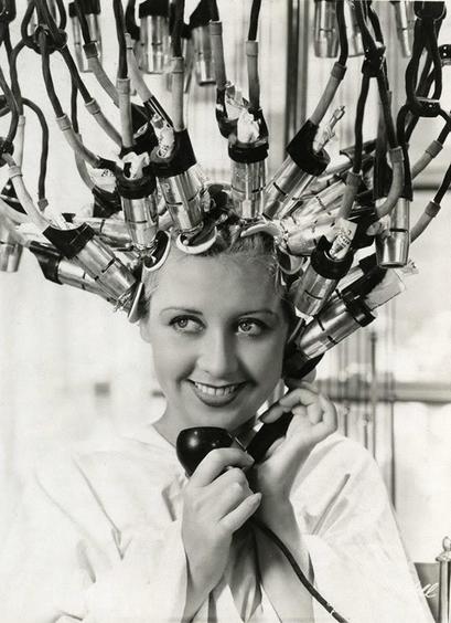 Joan blondell with strange devices on her washed hair. To make curles. She’s also on the phone.
