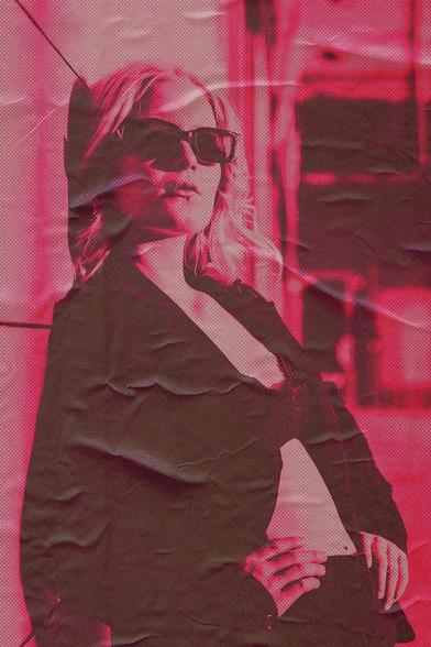 A woman with light hair wearing dark sunglasses and a blazer stands in a relaxed pose against a textured, pink-toned background. The image has a posterized effect with visible creases and folds, giving it a vintage, distressed look.
