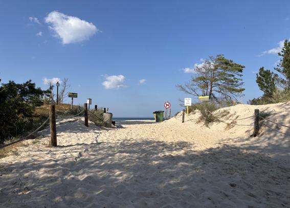 Ein Strandaufgang, dahinter ein leicht bewölkter Himmel.