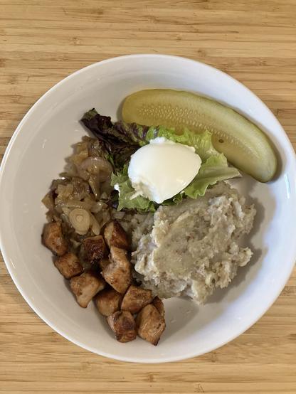A light coloured veg mash with cubes of browned pork, pickles, sauteed onions, and sour cream.