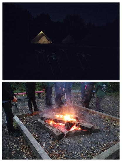 A two image collage. On top an illuminated “bell tent” in the dark. Nothing much else can be made out.

The bottom image is a blazing campfire edged by thick wood that resemble railway sleepers. The lower halves of 8 people can be seen standing around the fire, two of which on the right aren’t facing it. Benches can be seen behind the group.