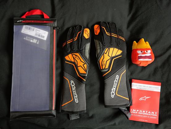 A pair of Alpinestars Tech-1 ZX V4 gloves, the zipper case and Anger.