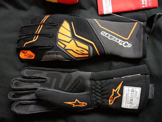 A pair of Alpinestars Tech-1 ZX V4 gloves. Black and orange.