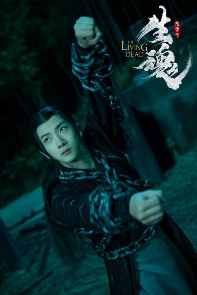Wen Ning in a pose with arms extended, right arm directly in front of him and left arm skyward, gaze fixed beyond the upper left edge of the frame. His robes are grey-stitched black over grey, and thick metal chains wrap around his torso forming an X over his chest, once around his waist, and encircling his wrists and forearms multiple times.