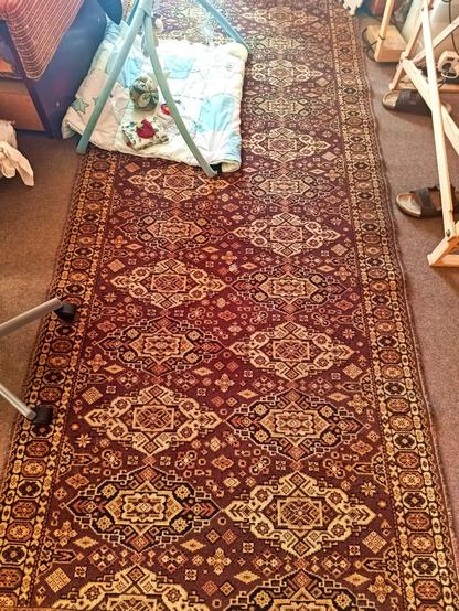 The old patterned rug found in the garage and then pressure washed in the previous toot. It's now on the floor of a room with some table and chair legs nearby and a baby play mat on top. The pattern looks nice, has good contrast and hides the small hole in the middle pretty well.