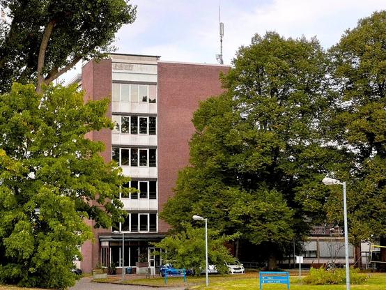 A medium-sized boxy building, signs on the lawn indicate that the building is located on a University campus.