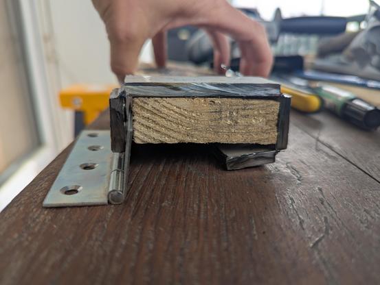 Une palette en bois vue de côté représente la poutre supérieure de la barrière du balcon sur lequel je vais accrocher le bar.
On voit des petits bouts de métal sur la face gauche de la palette, la face supérieure, la face droite, et un tout petit bout sur la face du bas à droite, qui va permettre de retenir le bar qui sera fixé à gauche