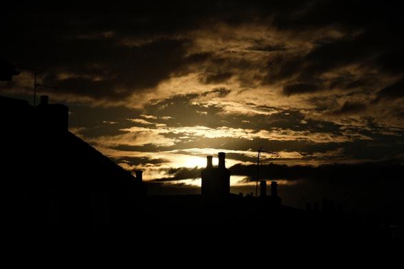 Dark and golden sunset behind a chimney.