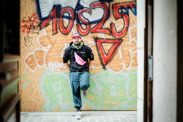 @dallo@pouet.chapril.org portant la banane de Solidaires, un keffieh vert en solidarité avec Gaza, une casquette de Solidaires Informatique et un sweat des Ramoneurs de Menhir, posé contre un mur taggué dont un gros 10s25 avec un triangle rouge symbole antifa du mouvement

 Maylis Rolland / Hans Lucas pour L’Humanité.