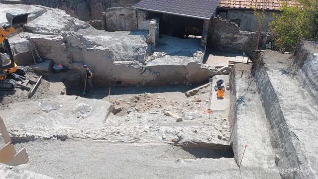 Scavi archeologici alla Villa dei Misteri a Pompei, con attrezzature e operai in campo.