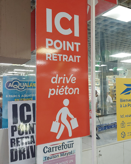 photo d'un panneau chez carrefour Toulon : "Ici point de retraite drive piéton" suivi d'un pictogramme dune personne portant deux sa cabas