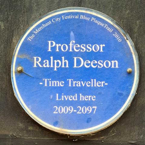 A blur plaque installed in the year 2000 which reads Professor Ralph Deeson, time traveller, lived here 2009 to 2097.
