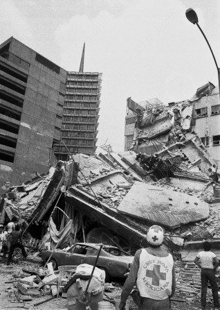 Edificios colapsados en Ciudad de México después del terremoto de 1985, con rescatistas y personal de Cruz Roja trabajando en el lugar.