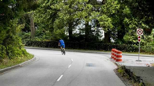 A single cyclist on a two-lane blacktop as they entered a tight curve.