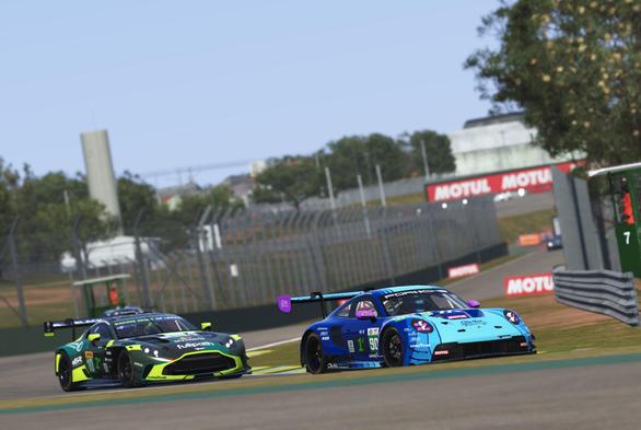 A Porsche 911 and Aston Martin entering a turn