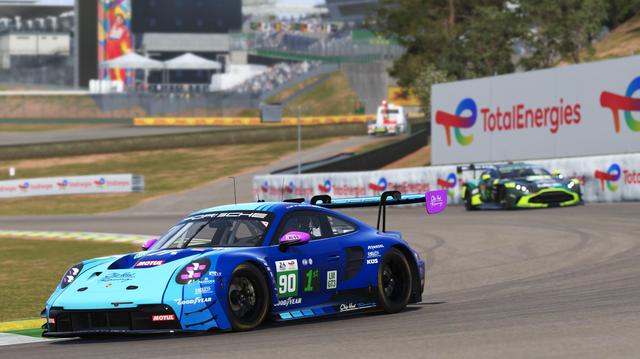 A Porsche 911 entering a turn with an Aston Martin following behind.