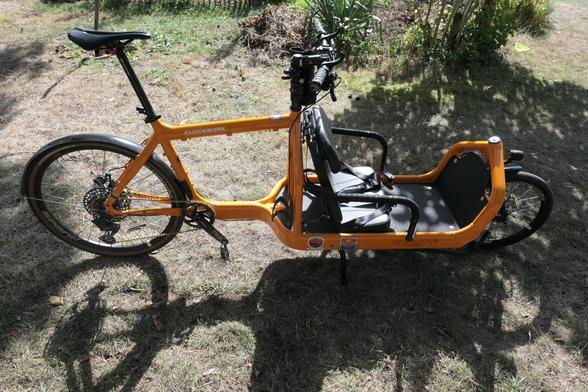 Seitenaufnahme eines Bullitt mit einem Convoy Classic Board, den seitlichen Metallbügeln des Bullitt Canopy sowie einem Klappsitz, auf dem theoretisch zwei kleine Kinder Platz finden.