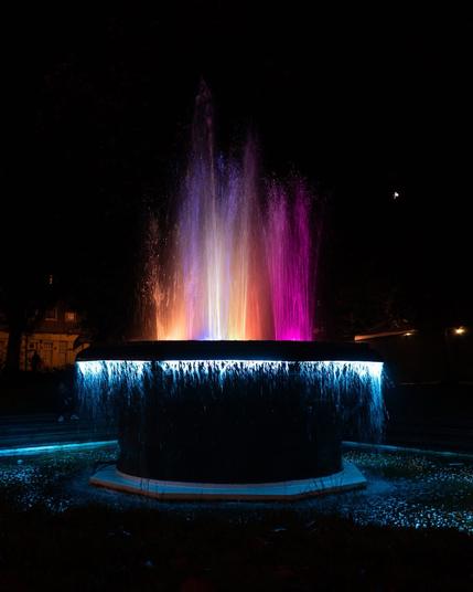 a fountain at night lit up by underwater lights