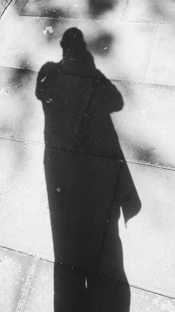 Long shadow of myself cast onto a brightly lit pavement