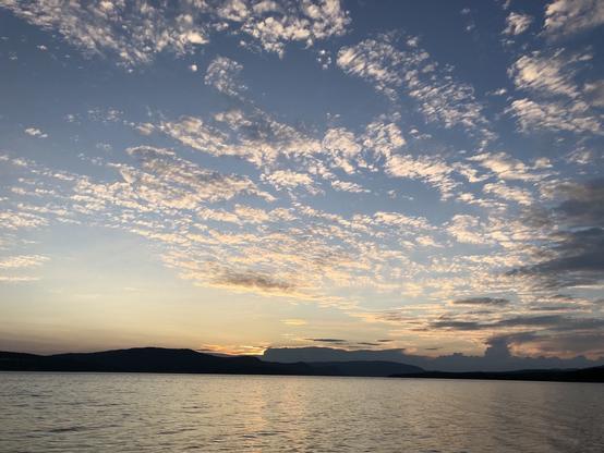 Coucher de soleil sur la pointe de Penouille du parc Forillon, en Gaspésie. Le ciel encore bleu est parsemé de petits nuages très haut dans l'atmosphère.