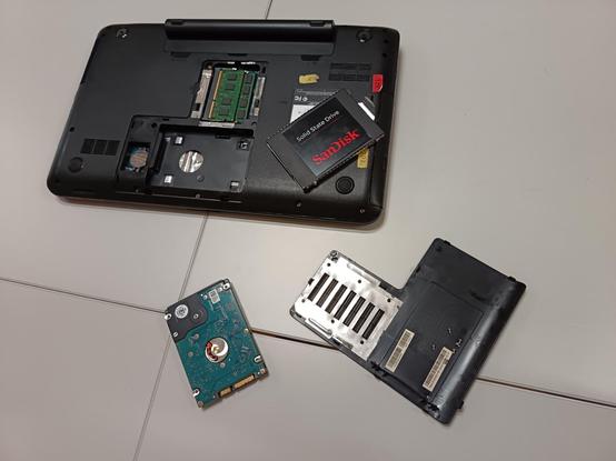 Ordinateur démonté par le dessous couvercle enlevé. Le disque dur HDD a été enlevé et le disque dur SSD est prêt à être installé.