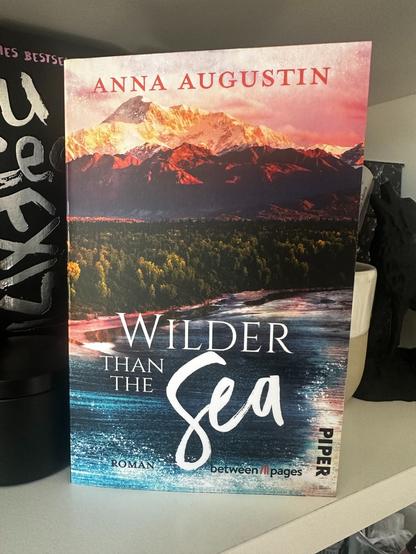 Das Cover des Buchs Wilder than the Sea (Alaskan Coast Guards 3) von Anna Augustin. Es steht in meinem Bücherregal