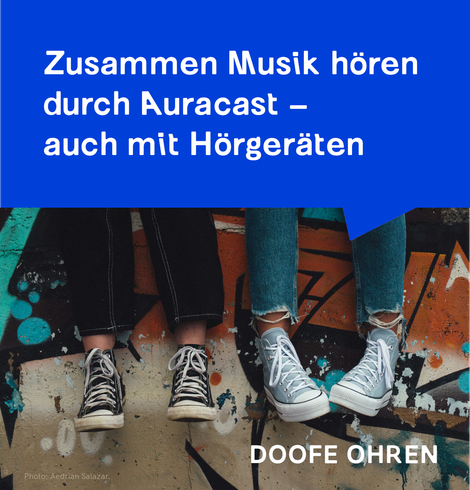 Ein Foto von zwei Paar Teenagerbeinen, die vor einer Graffiti-besprühten Wand baumeln. Darüber eine blaue Sprechblase mit weissem Text "Zusammen Musik hören durch Auracast - auch mit Hörgeräten" Unten über dem Foto in weisser Schrift "DOOFE OHREN".