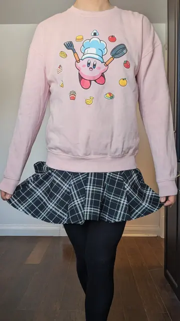 I may look cute with my pink Chef Kirby sweater, but my mind is full of dirty thoughts. Slightly lifting my black plaid skirt, I show off my a bit more of my legs.
But my legs are covered in tight, black stockings. 
What I'd really like is to be bent over and spanked. Am I being rewarded or punished? But why stop there?
Bend me over a chair and bind my hands down, cuff my ankles to the chair legs. Lift my skirt, drop my panties, and see what you have to work with.
Yes, spank me some more. Grope me and squeeze. Will you get the strap-on, or pull my cock between my legs for some edging or teasing? Maybe make me cum right away, then keep rubbing for some post-orgasm torture.
I'll probably start to wimper or moan, so why not gag me?
 Keep me quiet. I'm for playing, not for hearing. Let the drool hang from my mouth and pool below me as you smack or penetrate my small soft ass.
Keep me quiet as you torture my sensitive cock.
I can be yours to play with.
Or maybe I just look cute!