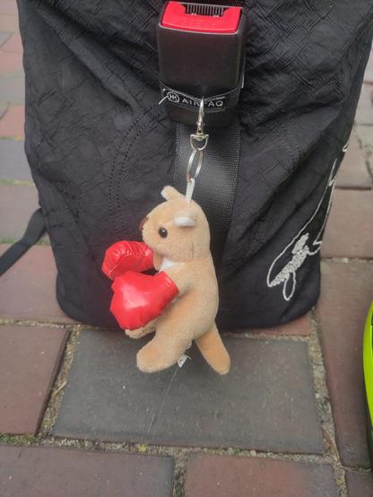 Ein an einer Tasche hängendes kleines Plüsch-Känguru mit roten Boxhandschuhen über den Vorderpfoten