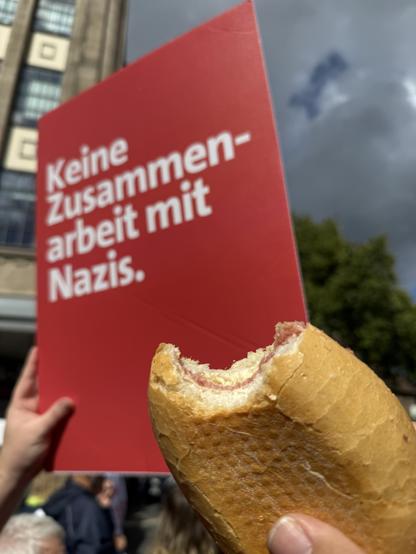 Mettbrötchen vor einem Schild mit der Beschriftung „Keine Zusammenarbeit mit Nazis.“
