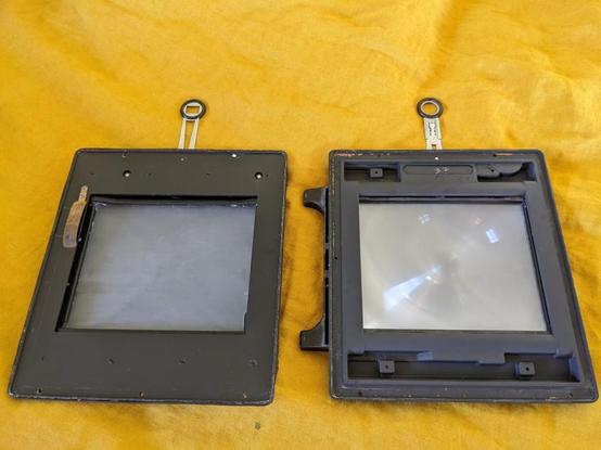 Closeup of Graflex and Graflock backs for large format film photography. Laid next to each other.