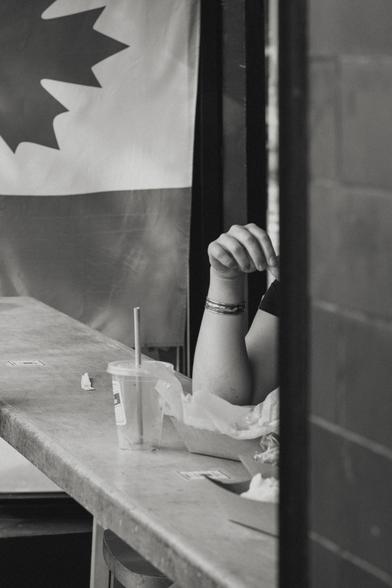 A person, out of frame enjoys their food in front of a Canadian flag.