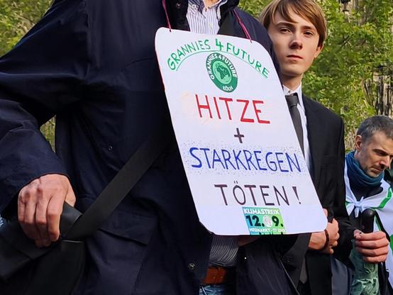 Mensch mit Demo Schild : Hitze und Starkregen töten!