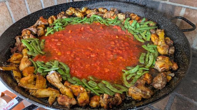 Paella en marcha. Carne, verdura y tomate.