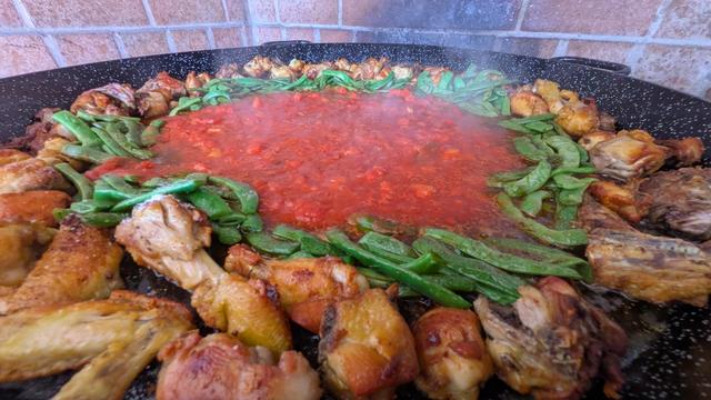 La misma paella en marcha. Carne, verdura y tomate pero desde un ángulo más cercano.