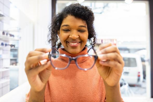 Mujer sonriente con gafas nuevas en una óptica. Clienta eligiendo gafas nuevas. (Getty Images)