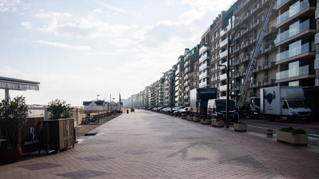 Color photo of the promenade at Duinbergen in the morning light. Appartment bildings to the right, beach cabins and cafes to the left.