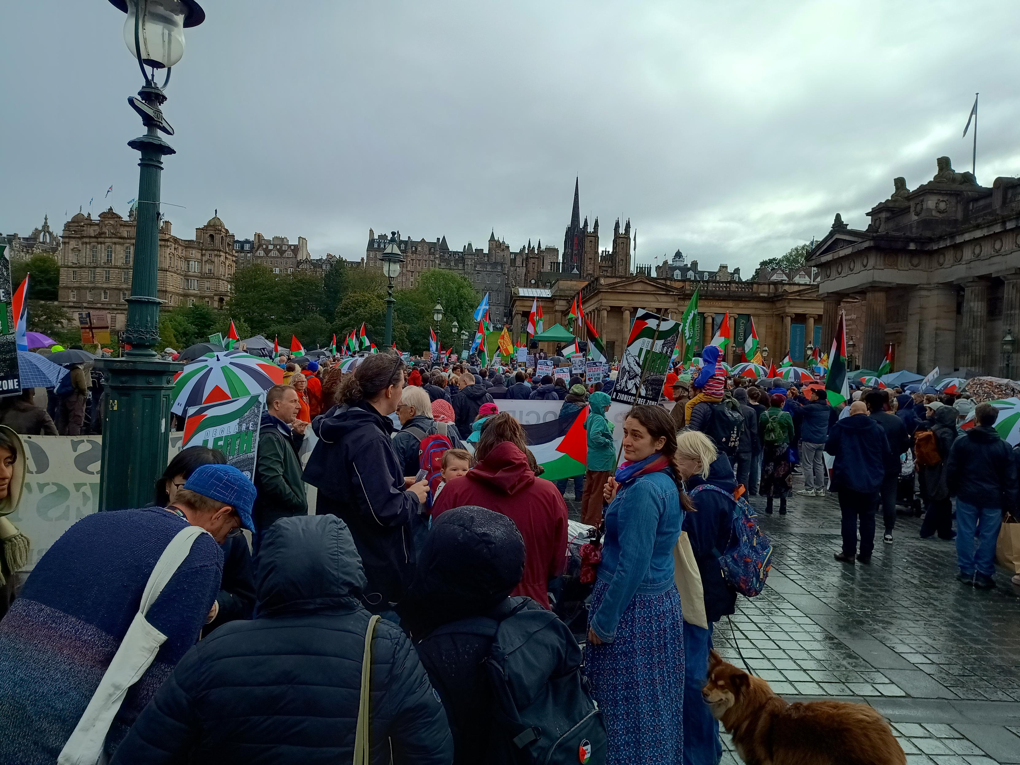 The large crowd listening to speakers in Edinburgh today. Many sheltering under umbrellas in Palestinian colours  & lots of Palestinian glagst