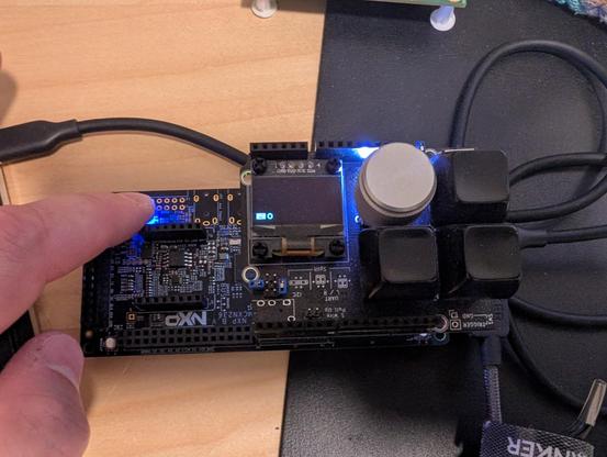 NXP dev board with a ZMK Uno shield, showing some basic info on the OLED, next two three keys and a rotary encoder.